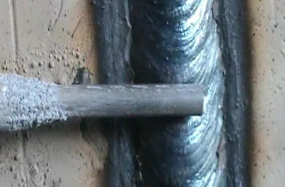 Рука сварщика выполняет вертикальный шов электродом Монолит LIFE 2 мм в труднодоступном месте конструкции