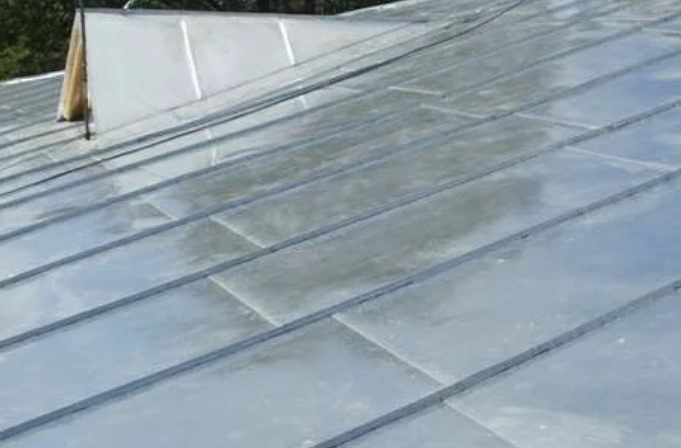 Оцинкованная кровля частного дома зимой покрытая равномерным слоем снега с установленными снегозадержателями для безопасности