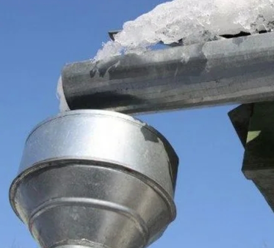 Оцинкованный водосточный желоб зимой с сосульками демонстрирующий отсутствие коррозии от солевых реагентов