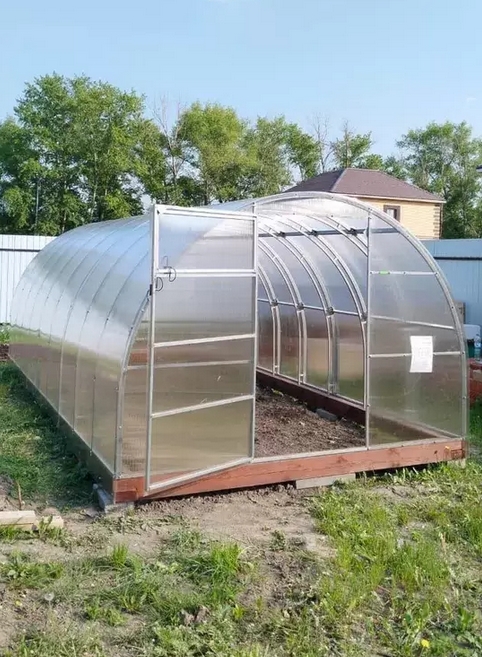 Арочная теплица из сотового поликарбоната на дачном участке весной