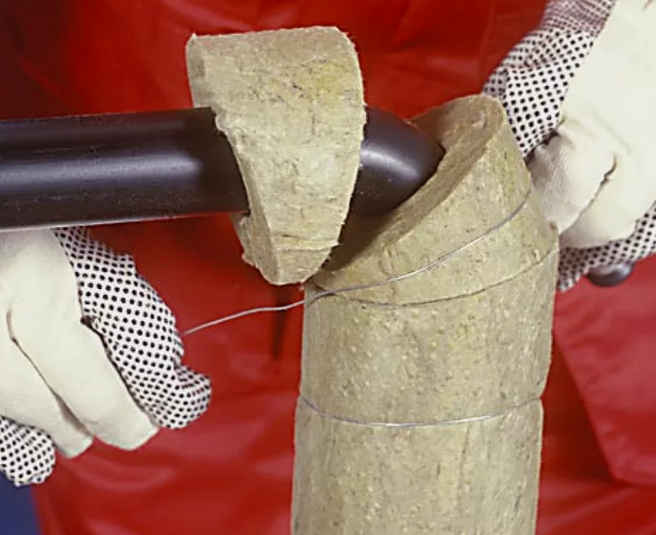 Утеплитель на трубопроводе, зафиксированный металлической проволокой для защиты от зимнего промерзания на дачном участке