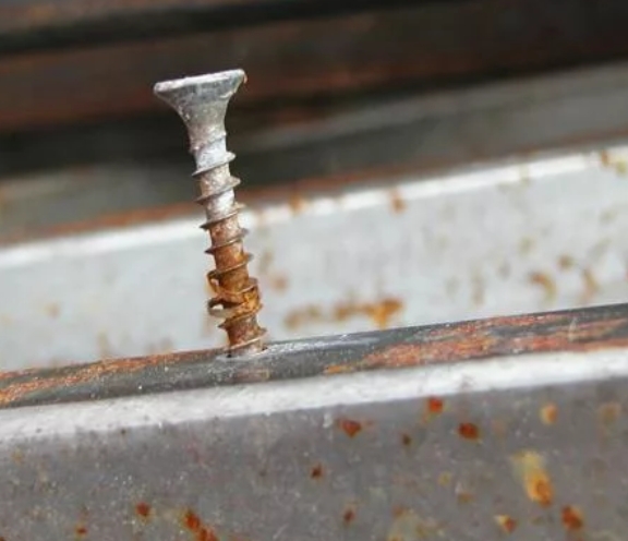 Крупный план ржавого самореза и рядом новый оцинкованный 
